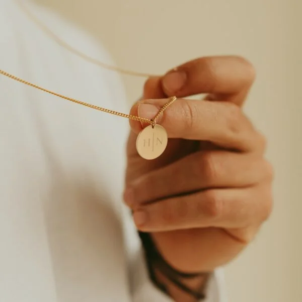 Man toont de ronde disc van de gepersonaliseerde mannen ketting