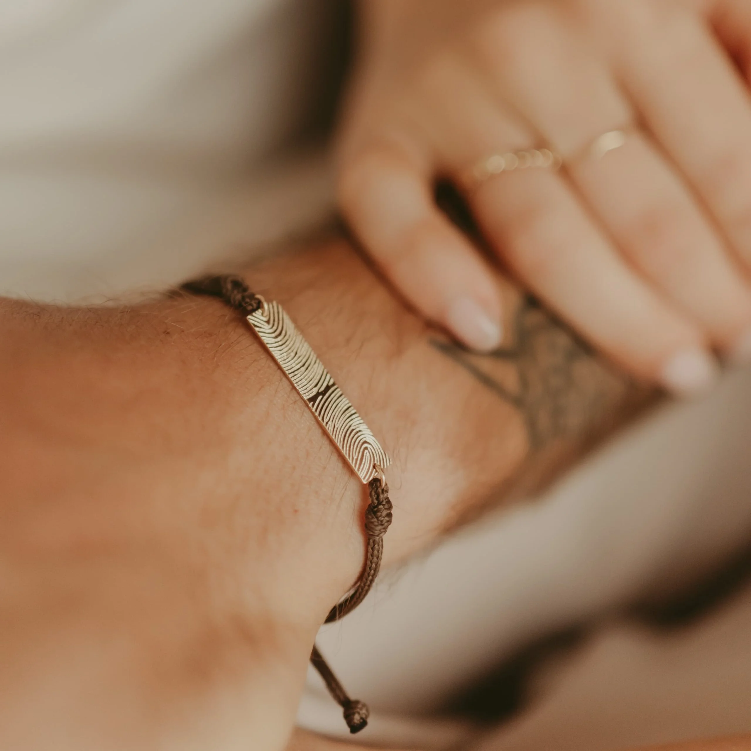 Vrouwenhand op een arm die een mannen armband met bar draagt